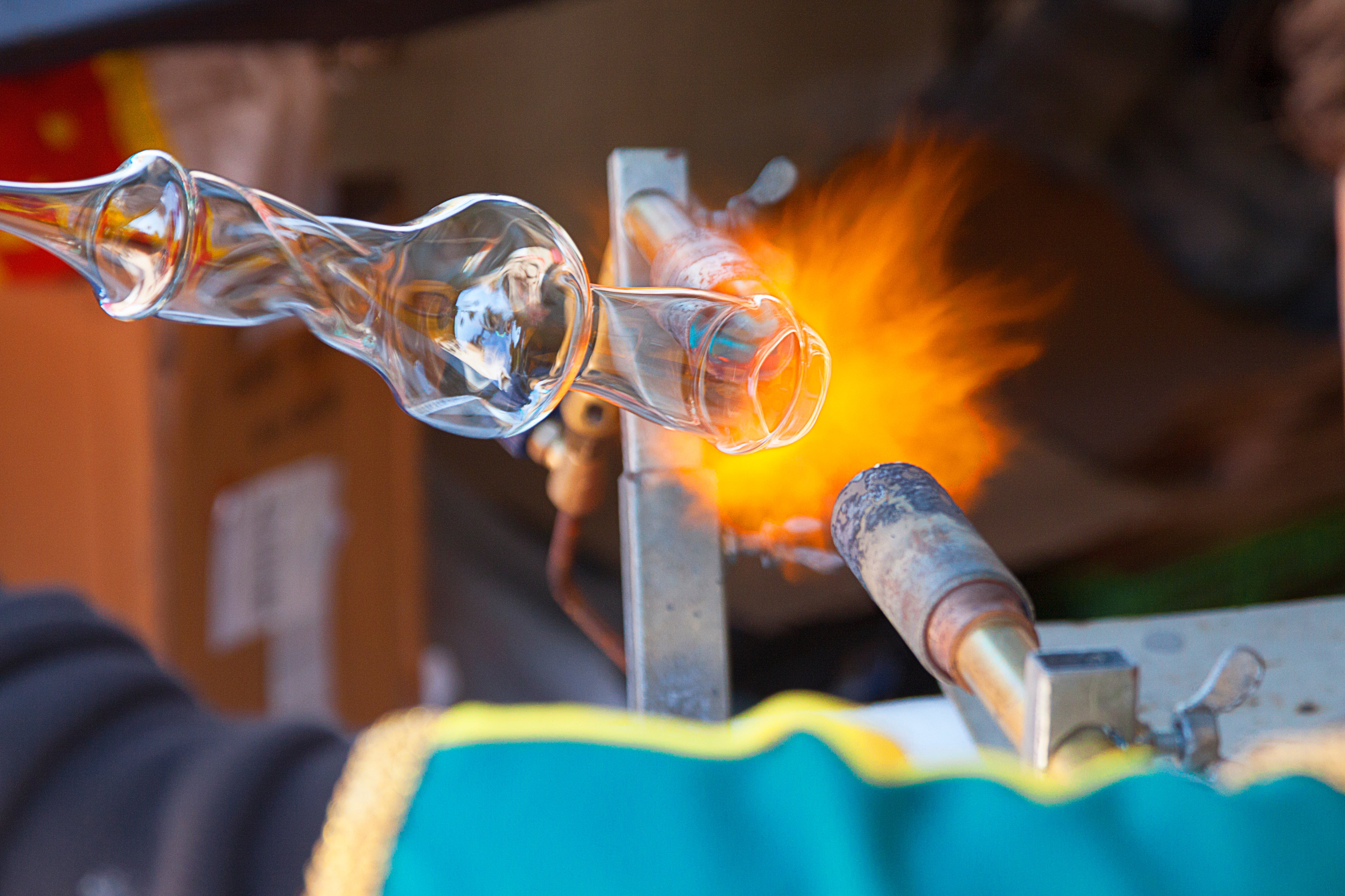 A burner heating a clear glass form during glassworking