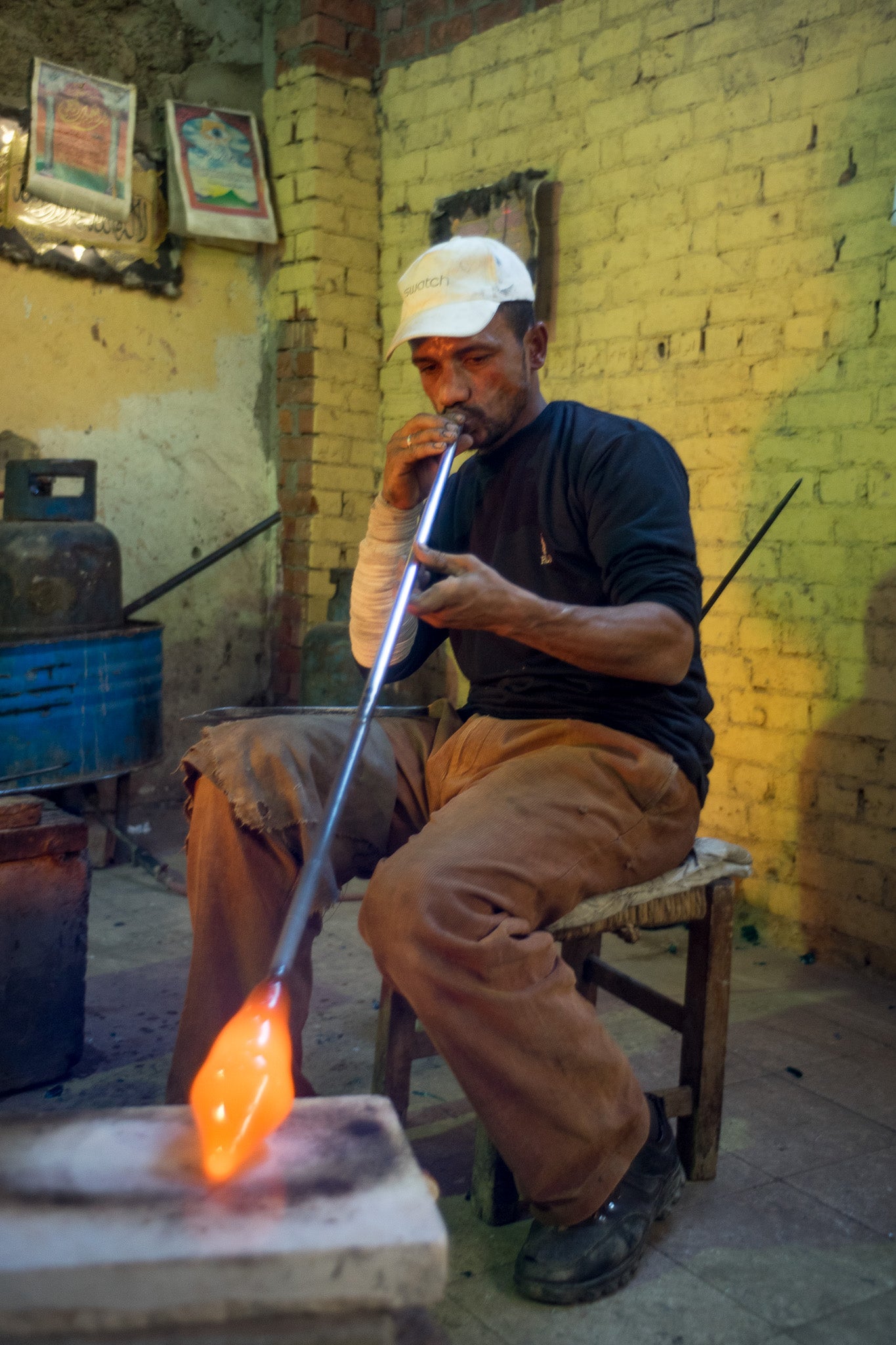 A glassblower using a blowpipe in a small workshop in Cairo