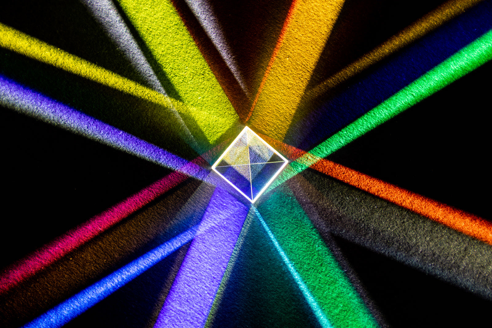 A glass prism casting colored light across a dark surface